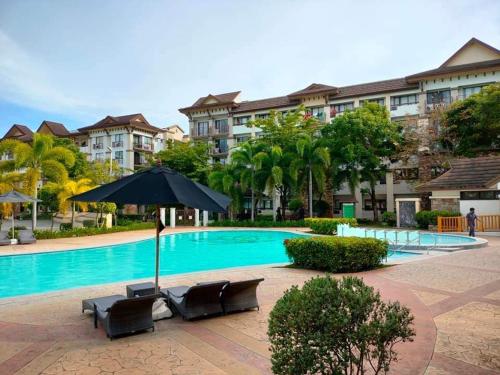 a swimming pool with chairs and an umbrella at One Oasis Condominium 2 Bedroom in Davao City