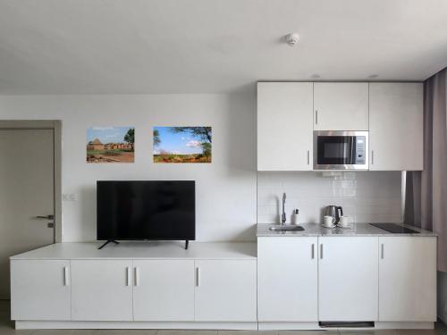 a kitchen with white cabinets and a flat screen tv at Résidences Plein Ciel in Abidjan