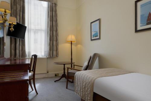 a hotel room with a bed and a desk and a window at The Lansdowne, Eastbourne in Eastbourne