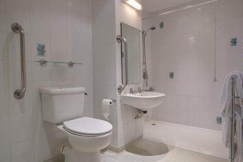 a white bathroom with a toilet and a sink at The Lansdowne, Eastbourne in Eastbourne