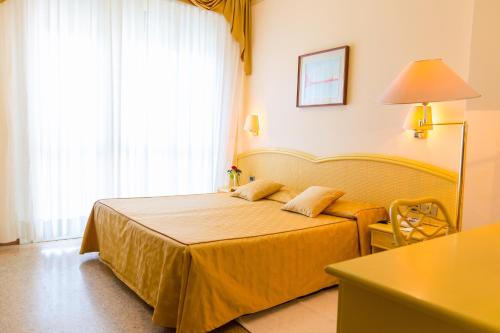 a bedroom with a bed and a table and a window at Hotel Principe in Bibione