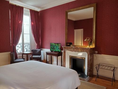 1 dormitorio con cama, espejo y chimenea en Logis des Tourelles, en Cognac