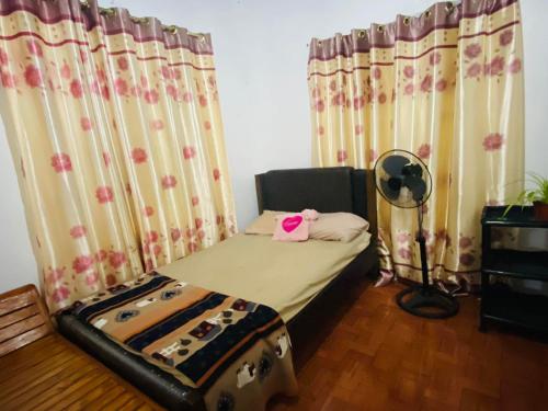 a bedroom with a bed and a fan and curtains at EASTDEE by Jaya in Lidlidda