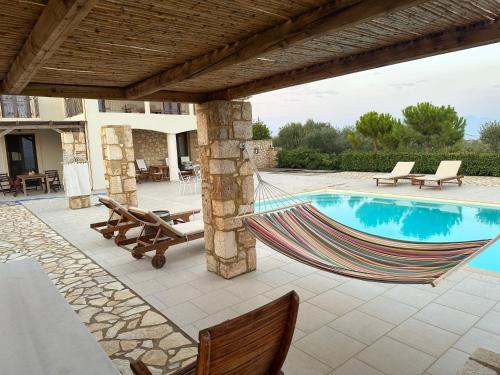 hamak na patio obok basenu w obiekcie Onirozo Koroni Private Villa w Koroni