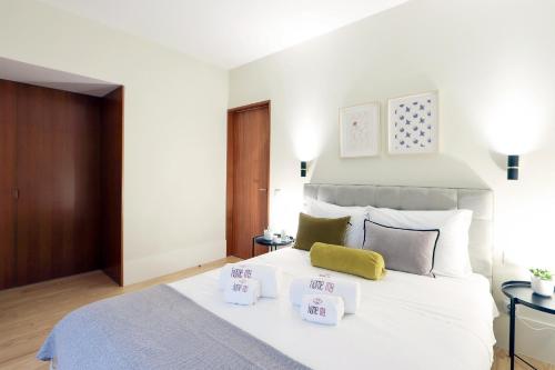 een slaapkamer met een groot wit bed met prijsborden bij HM - Almada City Stay in Porto