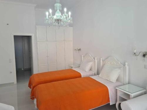 two beds in a white room with a chandelier at NN Rooms and Suites near Athens Airport in Spáta