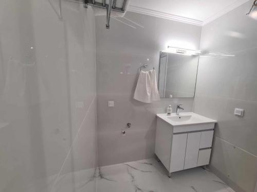 a white bathroom with a sink and a mirror at NN Rooms and Suites near Athens Airport in Spáta