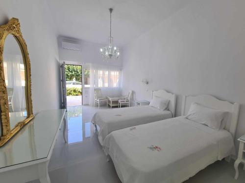 Cette chambre blanche comprend 2 lits et un miroir. dans l'établissement NN Rooms and Suites near Athens Airport, à Spáta