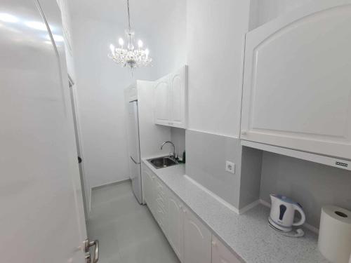 NN Rooms and Suites near Athens Airport في سباتا: مطبخ أبيض مع حوض ودواليب بيضاء