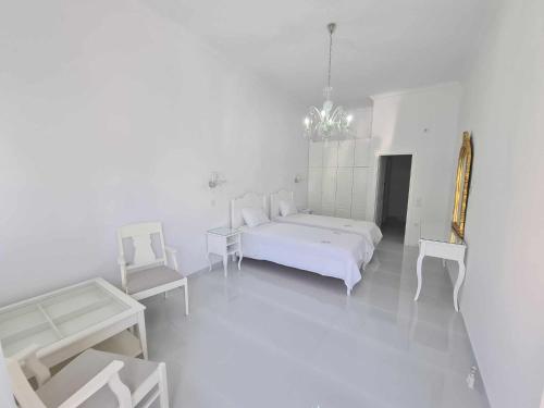 a white bedroom with a white bed and two chairs at NN Rooms and Suites near Athens Airport in Spáta