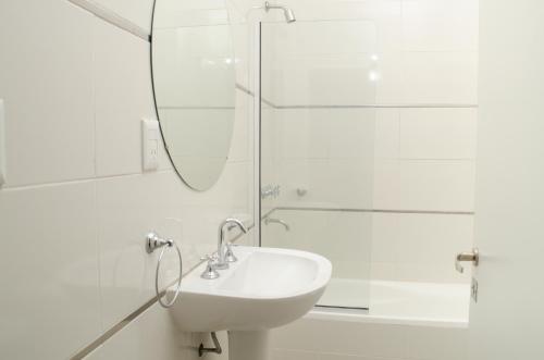 ein weißes Bad mit einem Waschbecken und einer Dusche in der Unterkunft LA MEJOR ESTADIA EN SANTIAGO DEL ESTERO in Santiago del Estero