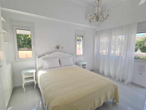 a white bedroom with a bed and two windows at NN Rooms and Suites near Athens Airport in Spáta