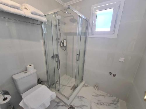 a white bathroom with a shower and a toilet at NN Rooms and Suites near Athens Airport in Spáta