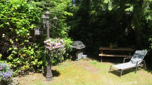 a garden with a street light and a bench and a grill at Cobble Wood and Bird Sanctuary Guest Houses in Tofino