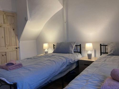 two beds in a room with two lamps on tables at Trent Bridge house in Nottingham