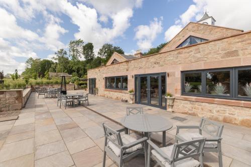 a patio with tables and chairs in front of a building at The Tempus at Charlton Hall Estate in Alnwick