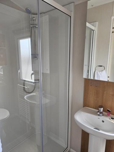 a bathroom with a glass shower and a sink at Private Caravan Camber Sands in Camber