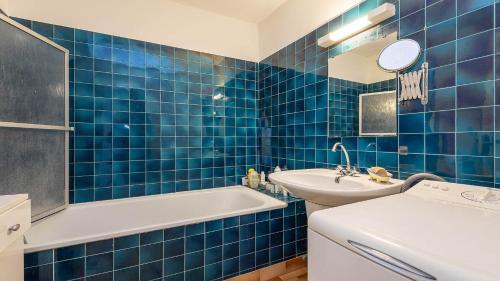 La salle de bains est pourvue de carrelage bleu, d'une baignoire et d'un lavabo. dans l'établissement La Colinne -113- 3 pers, au Cap d'Agde