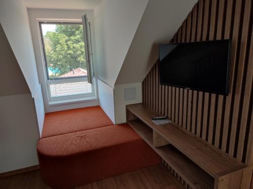 a living room with a red couch and a flat screen tv at apartmánový dom rodiny BÖJTÖS in Virthova Pustatina