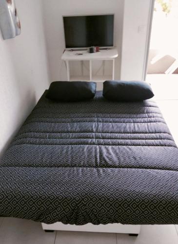 Cette chambre comprend un lit avec deux oreillers et une télévision. dans l'établissement Studio avec terrasse 2 personnes, au Lavandou