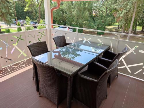 a glass table and chairs on a balcony at apartmánový dom rodiny BÖJTÖS Patince in Virthova Pustatina