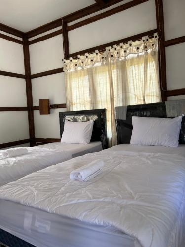 Dewa Daru Resort في كاريمونجاوا: غرفة نوم بسريرين وملاءات بيضاء ونافذة
