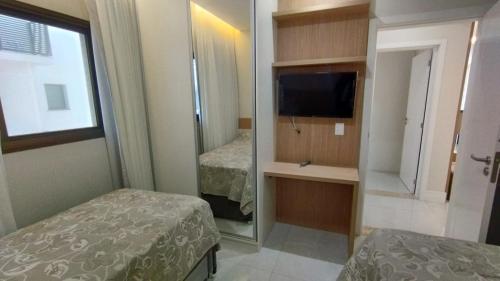 ein Schlafzimmer mit einem Spiegel, einem Bett und einem TV in der Unterkunft Departamento en Bombhinas in Bombinhas