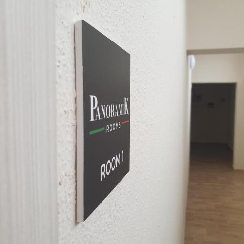 Une pancarte sur un mur qui dit "rory wilkes room" dans l'établissement PANORAMIK, à Acri