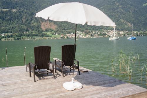 twee stoelen op een steiger met een paraplu bij Seevilla Lotte Ossiachersee in Annenheim