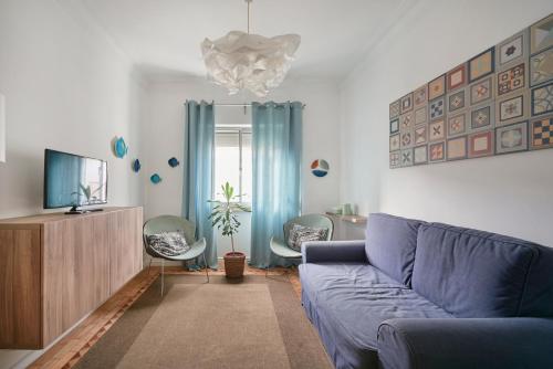 a living room with a blue couch and a tv at Bright and quiet apartment in Amadora