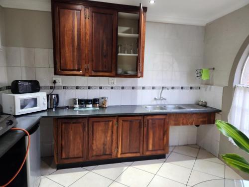 a kitchen with wooden cabinets and a microwave at Chalet 1 bedroom in Boksburg