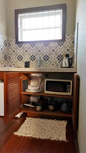 a kitchen with a microwave and a window at Solar das Pétalas Guest House in Florianópolis