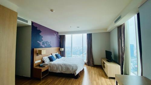 a hotel room with a bed and a large window at The H Tower Rasuna Suites Kuningan Jakarta By Villaloka in Jakarta