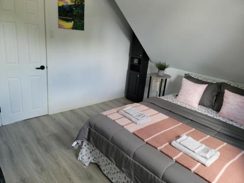 1 dormitorio con 1 cama grande con almohadas rosas en Comfy 1 bdrm apartment close to highway en Edmundston