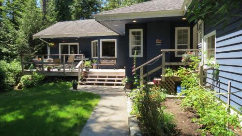 a blue house with a porch and a patio at Cobble Wood and Bird Sanctuary Guest Houses in Tofino