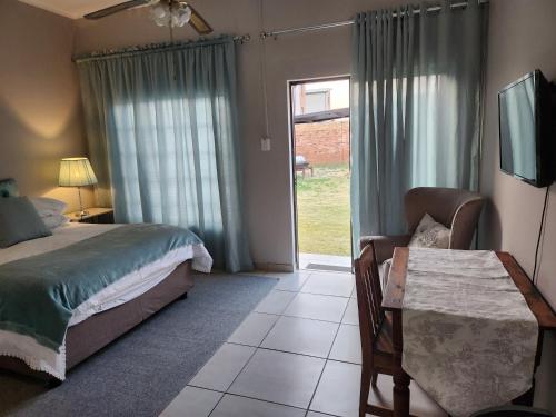 a bedroom with a bed and a table and a window at Sunny Guest Room in Boksburg