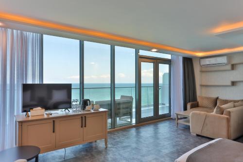 a living room with a television and large windows at Batumi View Luxury in Batumi