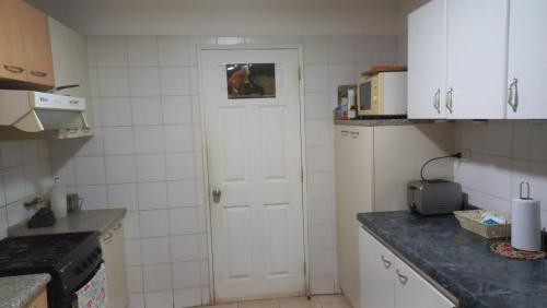 a kitchen with white cabinets and a white door at Pingueral in Dichato