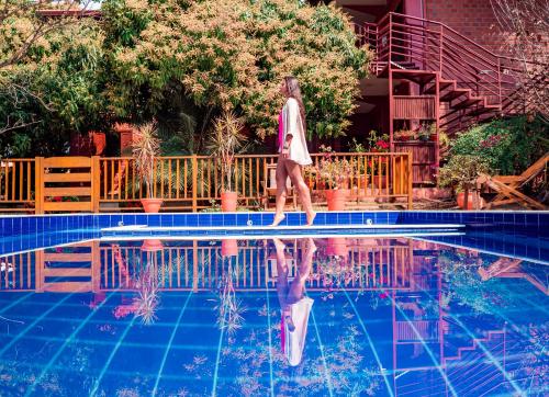 une femme qui marche dans l'eau à côté d'une piscine dans l'établissement Pousada Galeria Artes, à Bonito