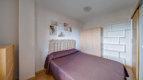a bedroom with a bed with a purple blanket at Apartamento de 1 dormitorio La Cala Villa Joyosa in Villajoyosa