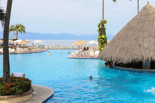 a swimming pool with people in the water at a resort at Departamento Frente a la Playa, Velas Vallarta in Puerto Vallarta
