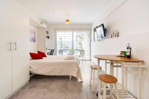 Espacio c/ Patio privado, lavadora y TV Premium في بوينس آيرس: غرفة نوم بسرير وطاولة في غرفة