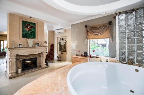 a large bathroom with a tub and a fireplace at Villa Amor in Pretoria