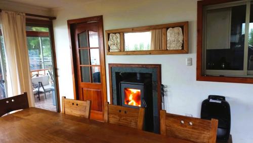 una sala de estar con chimenea y mesa de madera en Casa en Pingueral, en Dichato