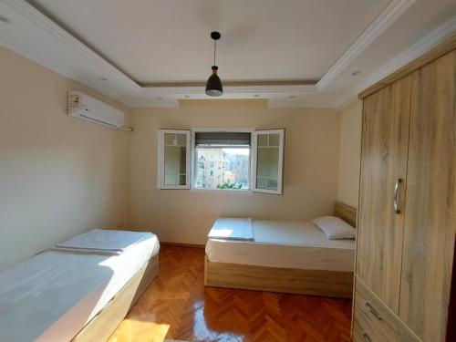 1 dormitorio con 2 camas y ventana en شقه فندقية رائعة في مركز مدينة الإسكندرية, en Alejandría