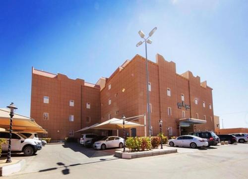 un grand bâtiment en briques avec des voitures garées dans un parking dans l'établissement Levant Hotel, à Najran