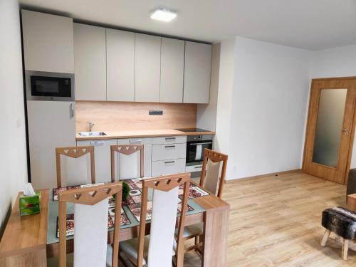 a kitchen with white cabinets and a table and chairs at Horský apartmán Hubertus č.19 in Karlova Studánka