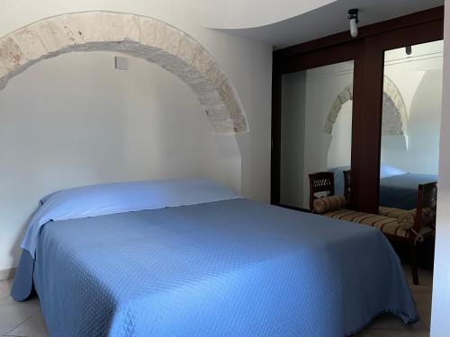 a bedroom with a blue bed and a mirror at Trullo Ronzicchio in Cisternino