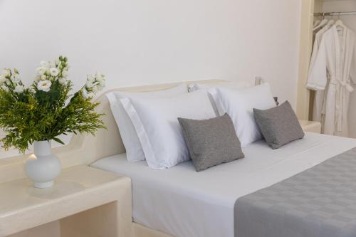 a white bed with a vase of flowers on a table at Theophrasti Suites in Foinikiá