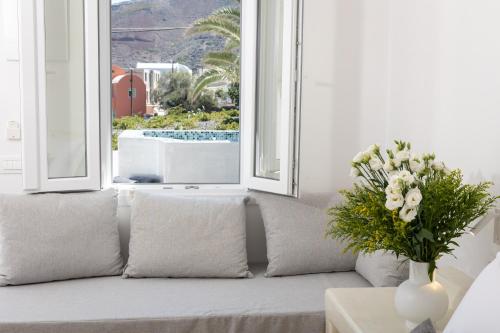a couch with a vase of flowers sitting in front of a window at Theophrasti Suites in Foinikiá